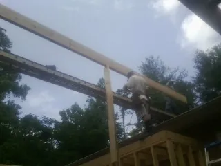 Carpenter setting a ridge beam over a new addition frame — Ice Dam Removal by Roofing Brothers in Southside