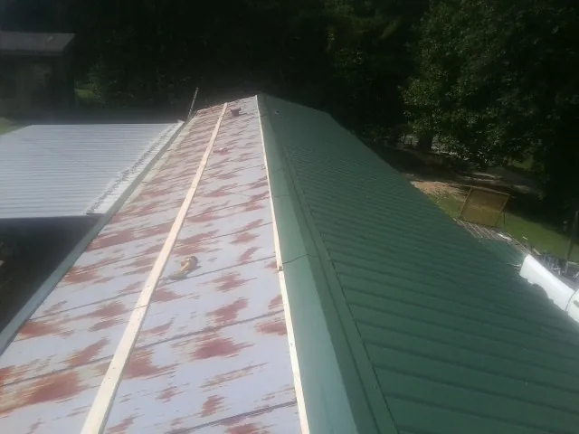 Old rusted panels beside newly installed green metal roofing — Wind Damage Roof Repair by Roofing Brothers in Southside