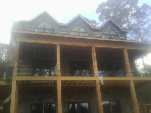 Dormers and porch framing on a large log home under construction — Roof Coating work by our crew in Southside