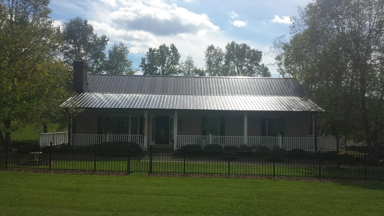Gray metal roof on a brick ranch with a full width front porch — Gutter Guard Installation work by our crew in Southside
