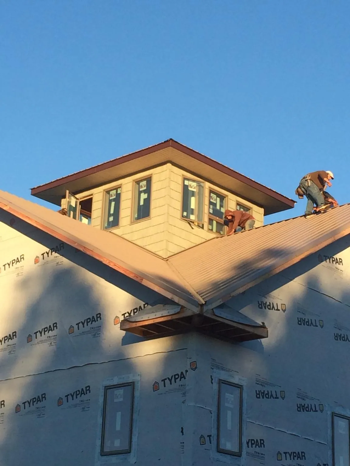 Roofers working around a rooftop cupola on a new metal roof at sunset — Roof Waterproofing in Southside by Roofing Brothers